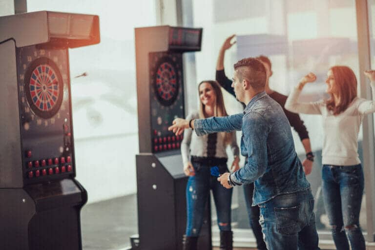 College friends playing a dartboard game, immersed in an enjoyable moment.