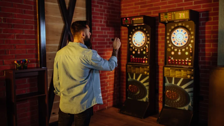 A photo of a dart board with colorful darts and a score sheet on a wooden table. (Best Dart Boards for Garage)