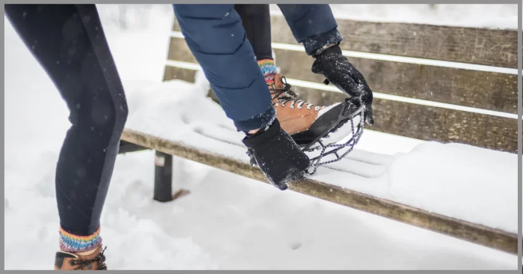 A young woman adjusting her boots with built in ice cleats 