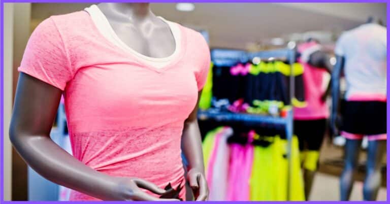 A mannequin wearing a pink t-shirt in a clothing store with racks of colorful sports clothing in the background.