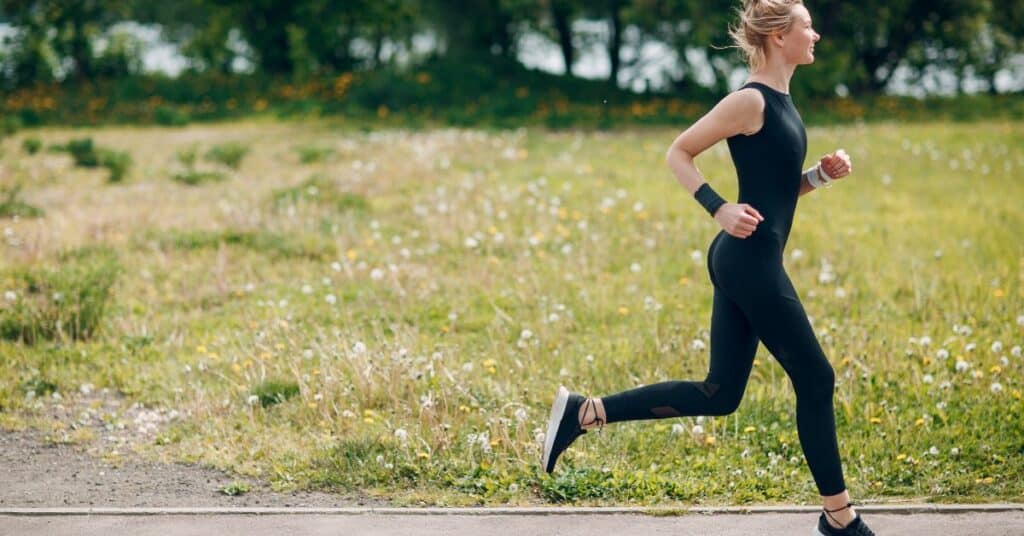 A young woman running on a gravel path in a park with trees and a lake in the background. Caption: Enjoying a morning jog in nature.