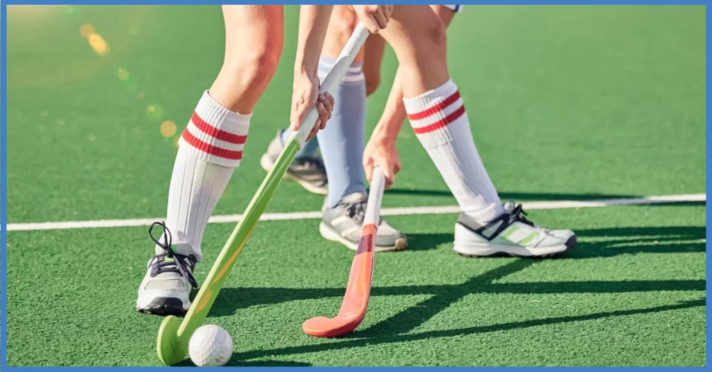 Two field hockey players in action on a green turf field. 