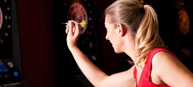 a woman playing dart with focusing the board point.