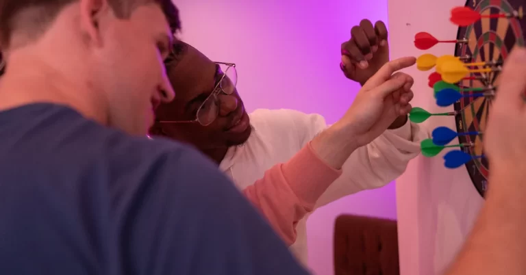 three friends playing dartboard and measuring the score on dartboard.